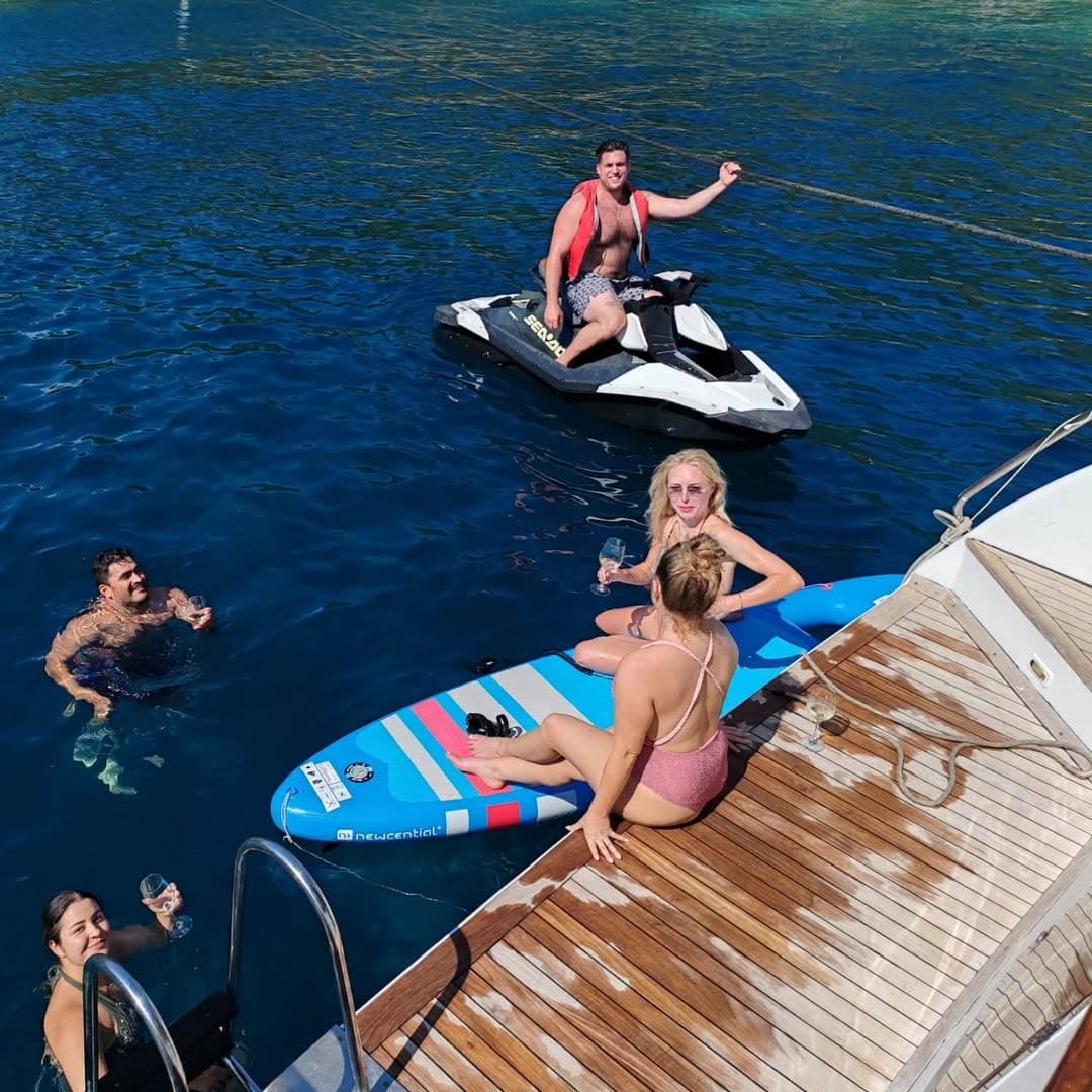 Child paddleboarding beside the gulet while the jetski is parked nearby